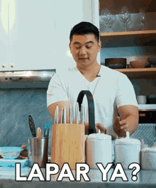 a man in a white shirt is standing in a kitchen with a knife block and the words lapar ya written on the counter