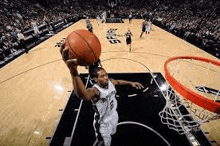 a basketball player is jumping in the air to dunk the ball during a basketball game .