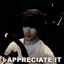 a man wearing headphones is sitting in front of a microphone with the words `` i appreciate it '' written below him .