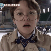 a young boy wearing glasses , a trench coat , and a bow tie is making a funny face .