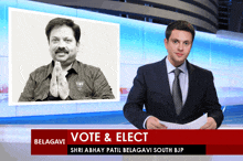 a man in a suit and tie holds a piece of paper in front of a sign that says vote and elect