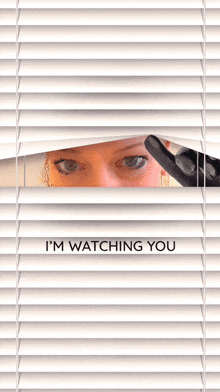 a woman looking through blinds with the words " i 'm watching you " on the bottom