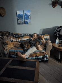 a woman sits on a couch with her dogs