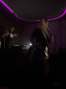 a blurry photo of a person dancing with a purple light behind them