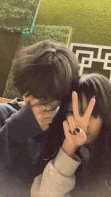 a boy and a girl are sitting next to each other and making a peace sign .