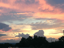 a sunset with a lot of clouds and trees in the background