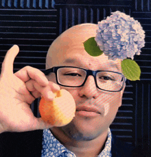 a man with glasses and a flower on his head holds an apple