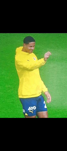 a soccer player wearing a yellow hoodie and blue shorts with avg written on them