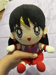 a person is holding a stuffed doll with a purple bow