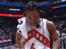 a basketball player wearing headphones and a raptors jersey