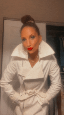 a woman wearing a white coat and red lipstick is standing in front of a door