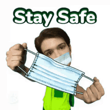 a man in a green vest is holding a face mask in front of his face and says stay safe .