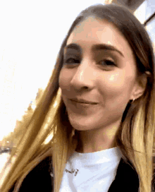 a close up of a woman 's face with a white shirt and a necklace that says " i love you "