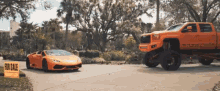 an orange car is parked next to an orange truck with a for sale sign on the side of the road