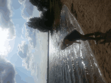 a woman is standing on a sandy beach near the water