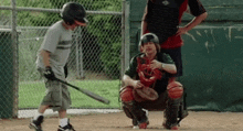 a young boy is swinging a bat while a catcher watches