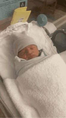 a newborn baby is wrapped in a white blanket and laying in a hospital bed