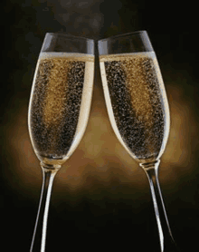 two glasses of champagne are toasting each other on a black background