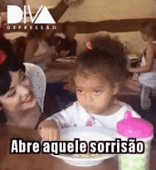 a little girl is sitting at a table with a bowl of food in front of her and a woman .