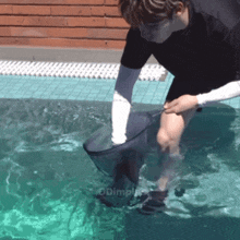 a man in a black shirt is standing in a swimming pool with the words dimple on the bottom right