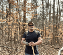 a man wearing sunglasses and a hat is standing in the woods