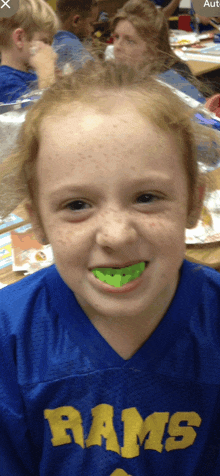 a young girl wearing a blue rams jersey smiles