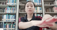 a woman stretches her arms in front of a bookshelf with a book titled ' a brief history of the world '