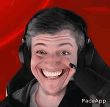 a man wearing headphones is making a funny face with the faceapp app on the bottom right