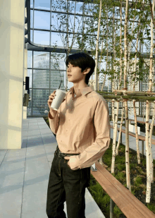 a young man holding a cup of coffee in front of a building