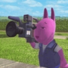 a pink stuffed animal is holding a video camera in its hand .