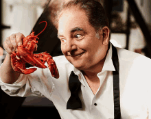 a man in a white shirt and black tie holds a lobster