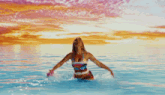 a woman in a bikini is in the water with her arms in the air and a shirt that says beach house