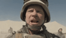 a close up of a soldier wearing a helmet and making a funny face .