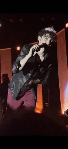 a man singing into a microphone while wearing a pink crown