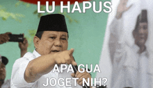 a man in a white shirt and black hat is pointing at the camera with the caption lu hapus