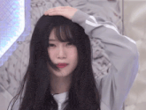 a girl with long black hair is holding her hand to her head