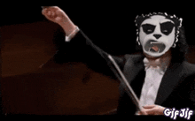 a man with a panda mask on his face is conducting an orchestra