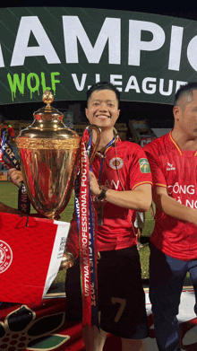 a man holding a trophy in front of a sign that says wolf v.league