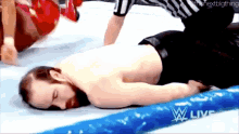 a man is laying on the floor in a wrestling ring with a referee .