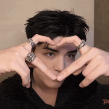 a man making a heart shape with his hands with rings on his fingers