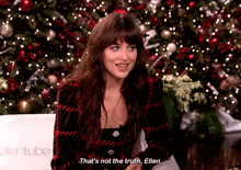 a woman sitting in front of a christmas tree says that 's not the truth ellen