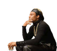 a man wearing a black turtleneck and leather pants is sitting down