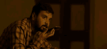 a man with a beard is holding a cell phone to his mouth in a dark room .