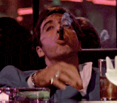 a man in a suit is smoking a cigar in a bar