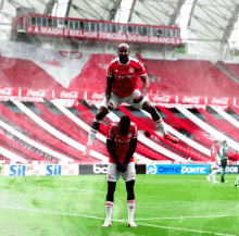 two soccer players on a field with a banner that says a maior e melhor torcida do rio grande in the background