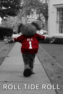 an elephant mascot is walking down a sidewalk wearing a big al jersey