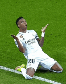 a soccer player wearing a white emirates jersey is kneeling on the field