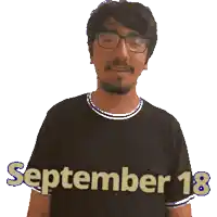 a man wearing glasses and a black shirt with september 18 written on it