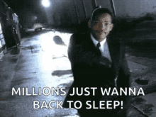 a man in a suit and tie is walking down a street at night and says millions just wanna back to sleep .