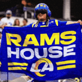 a man wearing a helmet is holding a blue rams house flag